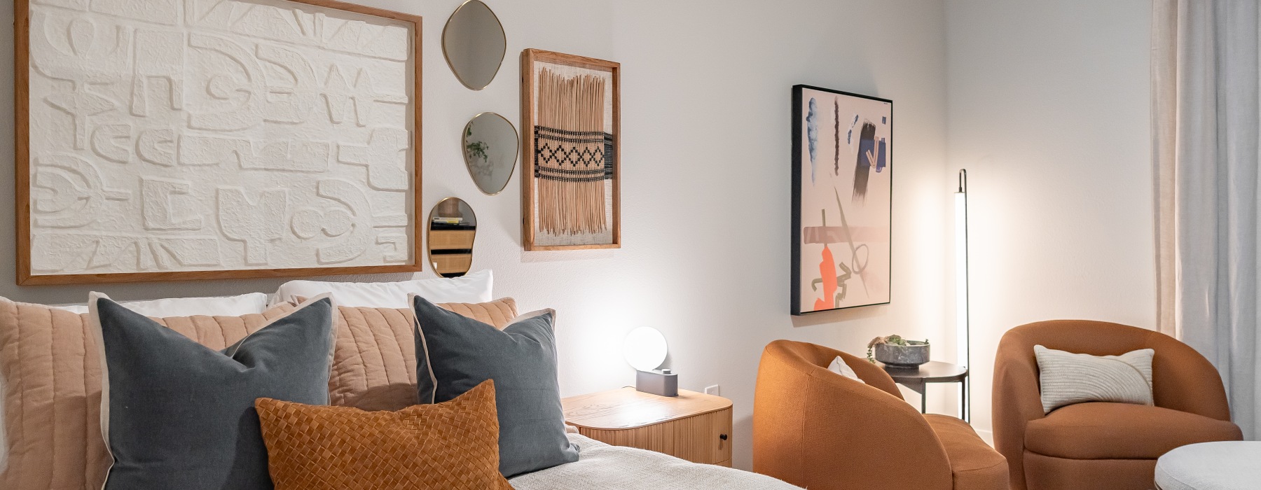 Stylishly decorated bedroom at The Blockyard with textured wall art, designer chairs, soft bedding, and ambient lighting for a cozy feel.
