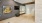 Fitness studio with a mirrored wall, ballet barre, mounted TV, abstract yellow flower artwork, and wooden flooring, creating a clean and functional workout space