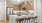 Kitchen area with wood cabinetry, stainless steel appliances, and a white island with a sink and seating for three on brown leather bar stools, lit by hanging pendant lights