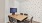 Small conference room with a wooden table, four chairs, a wall-mounted screen, and a white accent wall with abstract black patterns, creating a simple and functional meeting space